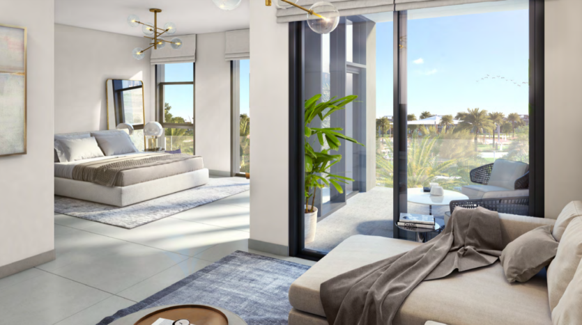 Un intérieur d&#039;appartement moderne comprenant un salon spacieux avec un canapé beige, attenant à une chambre avec de grandes fenêtres donnant sur les collines de Dubaï, mettant en valeur une verdure extérieure luxuriante et une lumière naturelle abondante.
