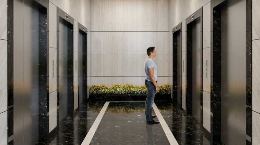 Un homme vêtu d&#039;un t-shirt bleu et d&#039;un jean se tient dans un ascenseur moderne avec des murs et des sols en marbre, des plafonniers blancs géométriques et des plantes décoratives.