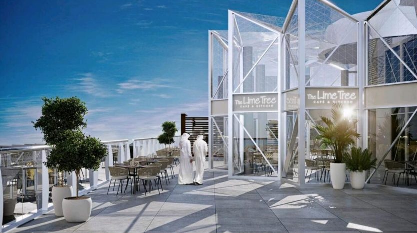 Un café moderne sur le toit nommé « le Tilleul » avec des structures en verre, des sièges extérieurs, des plantes en pot et deux personnes en conversation sous un ciel ensoleillé, surplombant la ville.