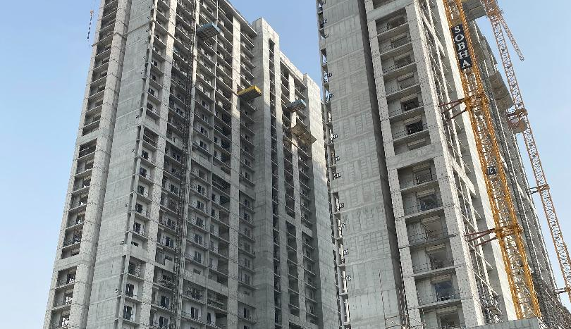 Photo d'un grand bâtiment en construction avec plusieurs grues et échafaudages contre un ciel clair à Creek Vistas, Dubaï.
