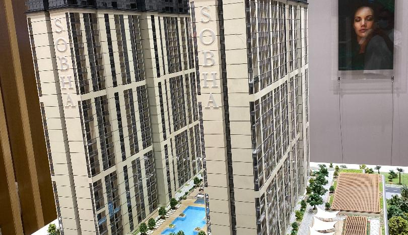 Une maquette détaillée du gratte-ciel Sobha Realty Creek Vistas à Dubaï, présentant des éléments de conception architecturale complexes, entourée de rues miniatures et d'un aménagement paysager comprenant des arbres et une piscine.