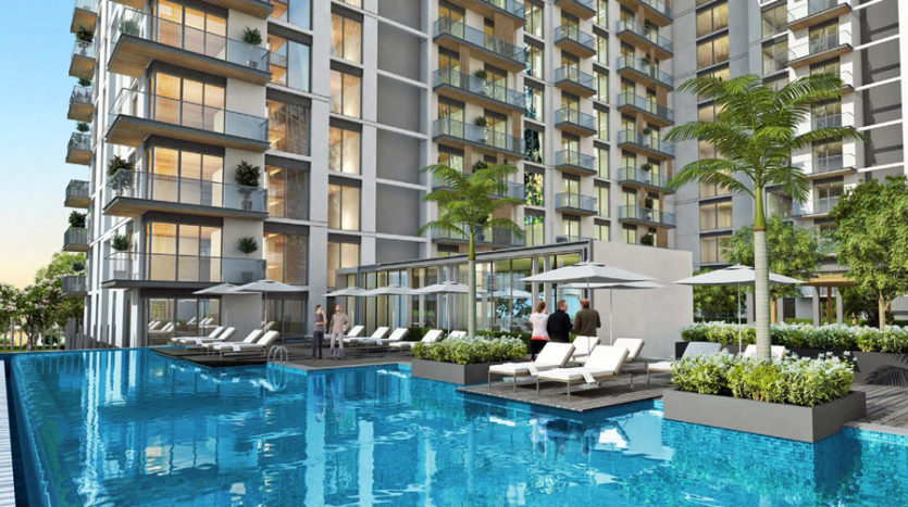 Espace piscine luxueux dans un immeuble d'appartements moderne de grande hauteur à Creek Vistas Dubai, doté de chaises longues et d'une verdure luxuriante, dont les résidents profitent des commodités.