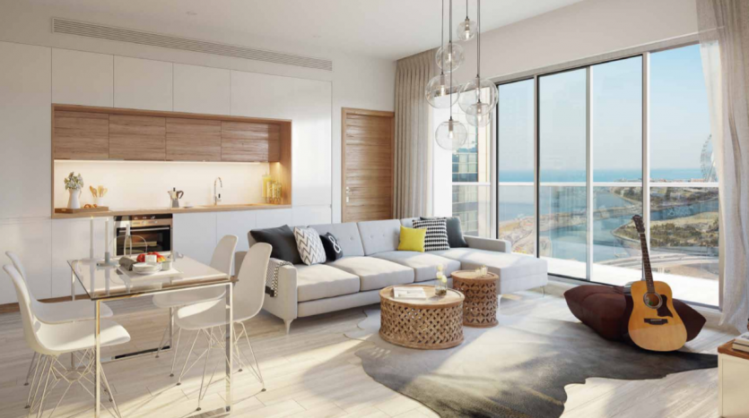 Intérieur d&#039;un studio moderne dans la marina de Dubaï avec un plan ouvert comprenant un salon avec canapé et guitare, un espace salle à manger et une cuisine, le tout donnant sur l&#039;océan à travers de grandes fenêtres en verre.