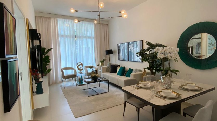 Salon moderne aux murs blancs, offrant une vue imprenable sur Dubaï, un coin repas avec une table dressée, un coin salon avec des canapés bleus et gris, un miroir rond au mur et des fauteuils moelleux.