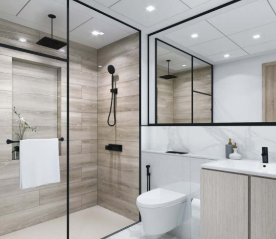 Salle de bain moderne de l&#039;Aria Résidence Dubai avec cabine de douche en verre, panneaux muraux en bois, toilettes en céramique blanche et vanité avec lavabo intégré. Design minimaliste avec des luminaires noirs et une petite plante.