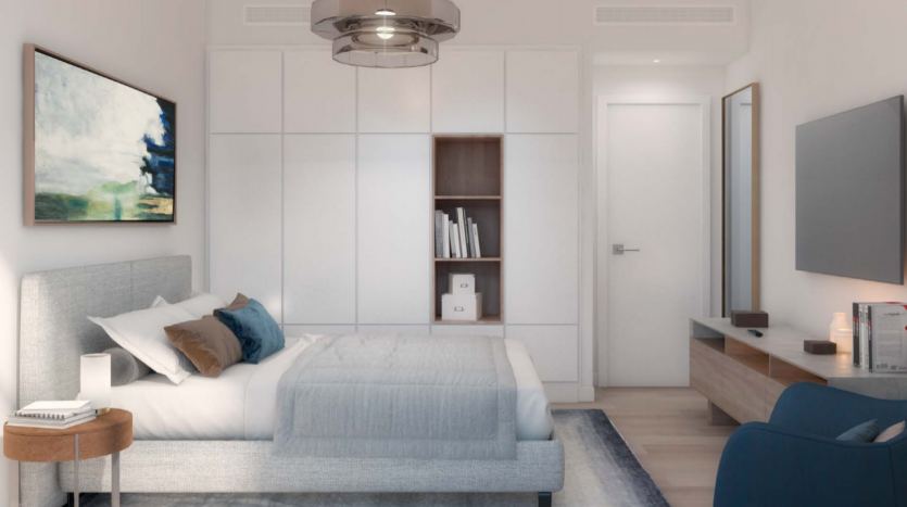Chambre moderne au design minimaliste comprenant un lit double, des armoires encastrées, un fauteuil et un grand tableau au-dessus du lit. La lumière naturelle entre par une fenêtre à gauche,
