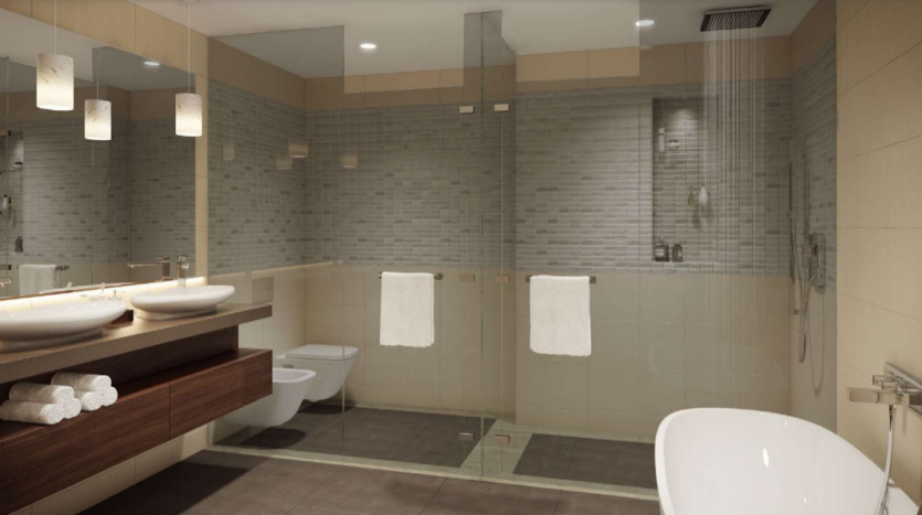Une salle de bains moderne et spacieuse au Jumeirah Living Marina Gate avec un éclairage tamisé, comprenant deux lavabos, des toilettes murales, un bidet et une baignoire autoportante. Des tons neutres et