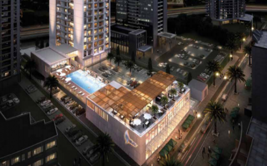 Vue aérienne nocturne du Studio One dans la marina de Dubaï, avec une piscine bien éclairée entourée de grands immeubles résidentiels et de parkings adjacents.