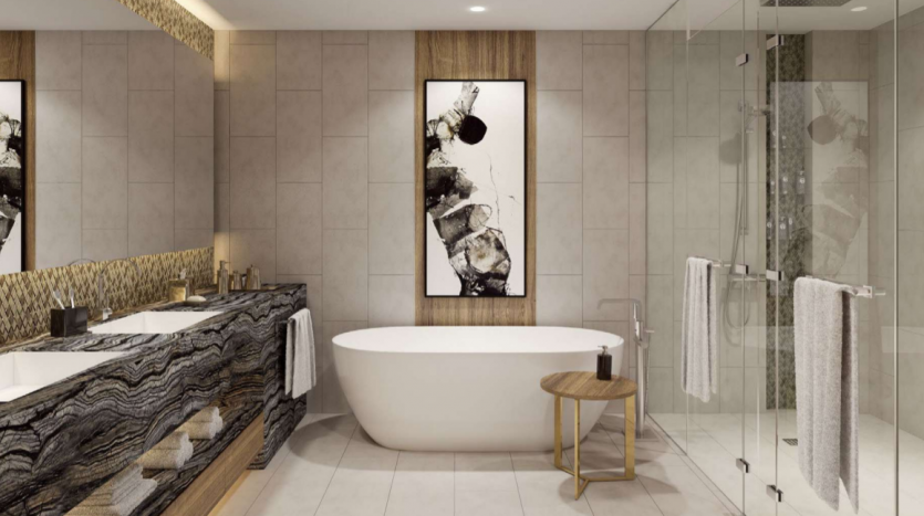 Intérieur de salle de bains moderne du Jumeirah Living Marina Gate comprenant une baignoire autoportante blanche, deux lavabos avec comptoirs texturés, des œuvres d&#039;art murales artistiques en noir et blanc et une cabine de douche en verre transparent.
