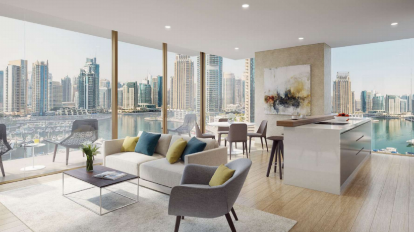 Salon moderne du Jumeirah Living Marina Gate avec une grande fenêtre donnant sur les toits de la ville et la marina. L&#039;intérieur comprend un canapé, des chaises et un coin bar cuisine, créant un espace lumineux.