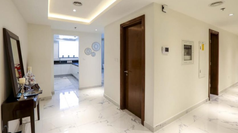 Couloir moderne avec sol en marbre, plusieurs portes en bois et éclairage de plafond élégant dans une villa de Dubaï. La décoration comprend une horloge murale et des œuvres d&#039;art encadrées.