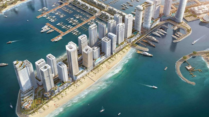 Vue aérienne d&#039;un développement urbain côtier avec des gratte-ciel près d&#039;une marina remplie de bateaux, à côté d&#039;une plage de sable aux eaux turquoise claires.