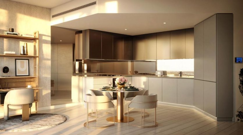 Une cuisine moderne avec des armoires marron élégantes, des appareils électroménagers intégrés et une table à manger ronde pour deux à Regalia Dubaï, éclairée par une lumière chaude et naturelle.