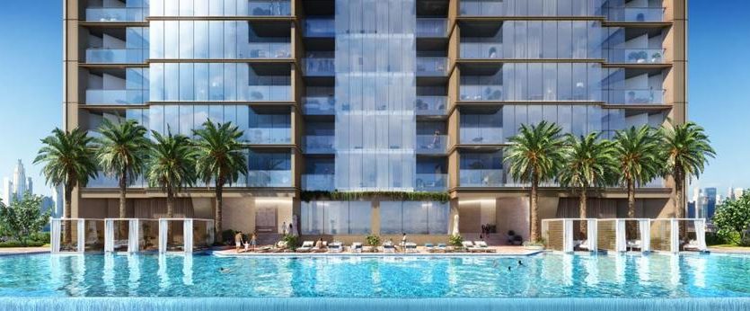 Immeuble d&#039;appartements moderne avec une grande piscine au premier plan, flanquée de palmiers et de chaises longues, surplombant les toits de Dubaï.