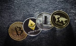 Cuatro tipos diferentes de criptomonedas, entre ellas Bitcoin, Ethereum, Litecoin y otra, dispuestas sobre una superficie de textura oscura para simbolizar el uso de Bitcoin para comprar un piso en Dubai.