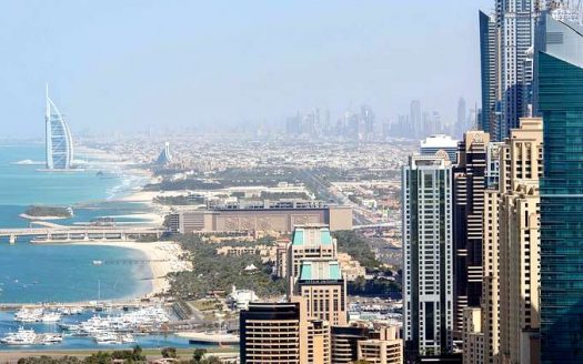 L'horizon de Dubaï avec des gratte-ciel modernes, le Burj Al Arab et des vues sur le littoral et le port, idéal pour ceux qui cherchent à investir dans l'immobilier, sous un ciel bleu clair.