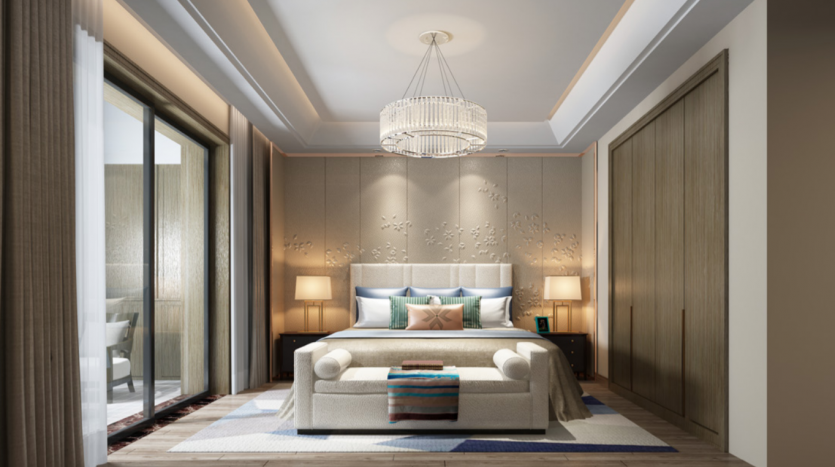 Chambre élégante et moderne comprenant un grand lit avec des oreillers décoratifs, un panneau mural artistique, un lustre, un banc et une porte coulissante menant à un balcon dans l&#039;un des meilleurs programmes immobiliers de Dubaï.