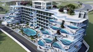 Vue aérienne d'un hôtel moderne de plusieurs étages en bord de mer doté de balcons avec piscines privées, de terrasses paysagées et d'une grande piscine centrale, situé dans le parc Samana avec vue sur la verdure luxuriante.