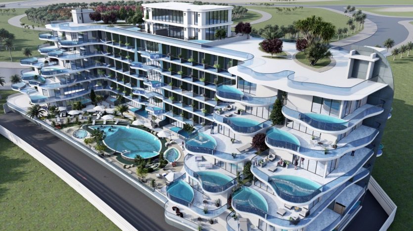 Vue aérienne d&#039;un hôtel moderne de plusieurs étages en bord de mer doté de balcons avec piscines privées, de terrasses paysagées et d&#039;une grande piscine centrale, situé dans le parc Samana avec vue sur la verdure luxuriante.
