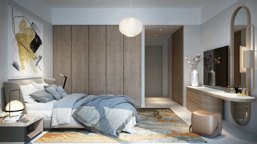 Intérieur de chambre moderne comprenant un lit gris moelleux avec des couvertures froissées, des meubles en bois élégants, un éclairage tamisé et des œuvres d&#039;art murales abstraites dans la vallée de Dubaï, créant une ambiance chaleureuse et contemporaine.