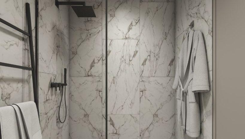 Une salle de bain moderne dotée d&#039;une douche à l&#039;italienne entourée de portes vitrées aux cadres noirs, sur fond de murs et de sols en marbre. Il y a des serviettes soigneusement suspendues sur un côté, brodées de l&#039;élégant Reg