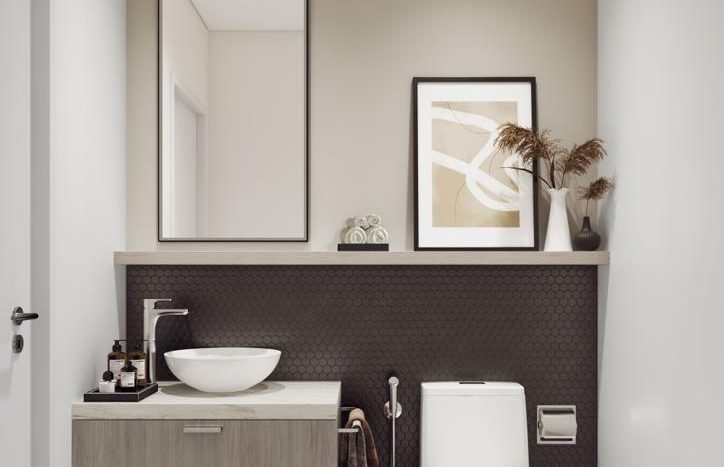Une salle de bains moderne dans Harrington House comprenant des toilettes élégantes à côté d&#039;une vanité en bois avec un lavabo et des articles de toilette. Un miroir encadré et des œuvres d&#039;art abstraites sont suspendus au-dessus, complétés par des plantes en pot.