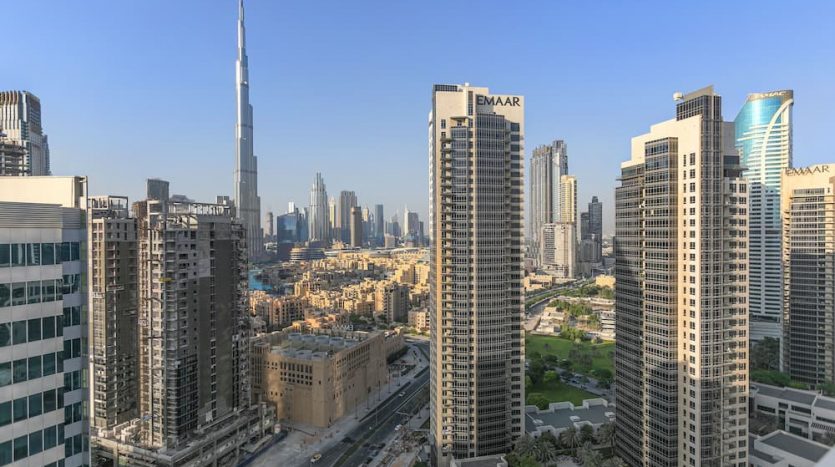 Une vue panoramique du centre-ville de Dubaï, notamment de la place Marquise, des gratte-ciel comme le Burj Khalifa, du ciel bleu clair et des routes urbaines.