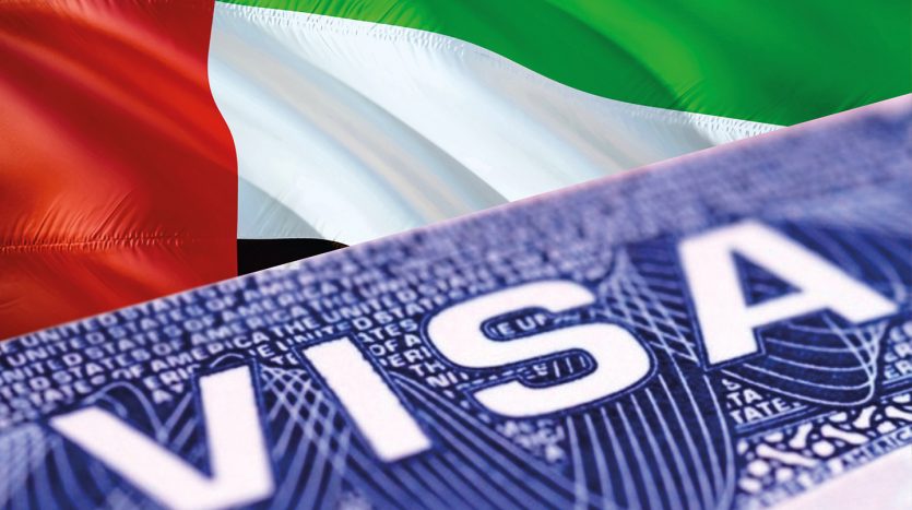 Gros plan sur un visa d&#039;investisseur américain superposé au drapeau partiellement visible des Émirats arabes unis en arrière-plan.