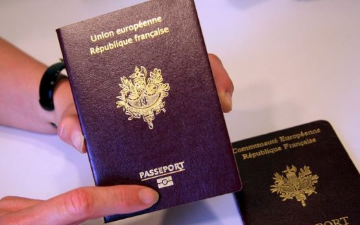 Une personne titulaire d'un passeport français avec "Union Européenne, République Française" et l'emblème national sur la couverture, ainsi que des documents pour acheter un appartement à Dubaï.