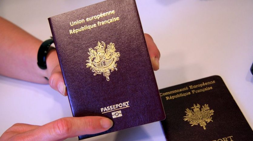Une personne titulaire d'un passeport français avec "Union Européenne, République Française" et l'emblème national sur la couverture, ainsi que des documents pour acheter un appartement à Dubaï.