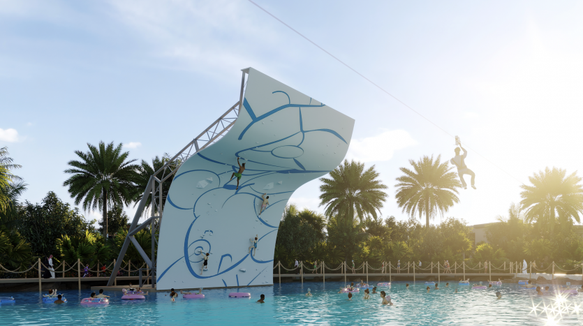 Texte alternatif : une personne utilisant une tyrolienne au-dessus d&#039;une piscine bondée à Damas Hills 3, descendant d&#039;une haute tour artistiquement conçue avec un motif de vagues bleues, entourée de palmiers