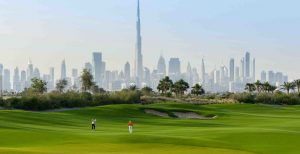 Deux golfeurs sur un parcours vert vif avec un bunker de sable, mettant en avant une vue panoramique sur les toits de Dubaï, y compris le Burj Khalifa, situé dans l'un des meilleurs quartiers de Dubaï.