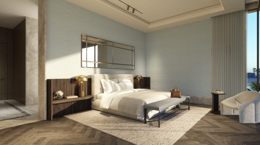 Une chambre moderne dotée d&#039;un lit king-size avec une literie blanche Six Senses, un mur bleu texturé, du parquet, de grandes fenêtres avec lumière du jour et un mobilier élégant comprenant un banc et un fauteuil.