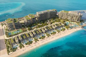 Вид с воздуха на роскошный пляжный курорт Six Senses с рядами вилл, ведущих к многоэтажным зданиям, расположенным между прозрачным голубым морем с одной стороны и пышными садами с другой.