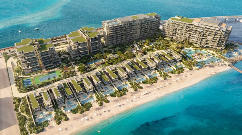Vue aérienne d&#039;un complexe hôtelier de luxe Six Senses en bord de mer avec des rangées de villas menant à des bâtiments à plusieurs étages, nichés entre une mer bleu clair d&#039;un côté et des jardins luxuriants de l&#039;autre.