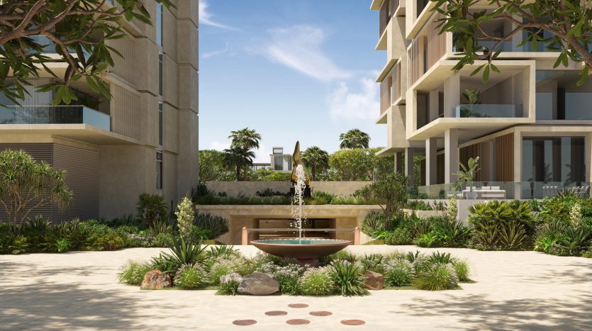 Luxueux parcours du complexe Six Senses bordé de verdure luxuriante, présentant un design symétrique avec des appartements modernes de chaque côté, une fontaine décorative centrale et une vue dégagée menant aux bâtiments éloignés.