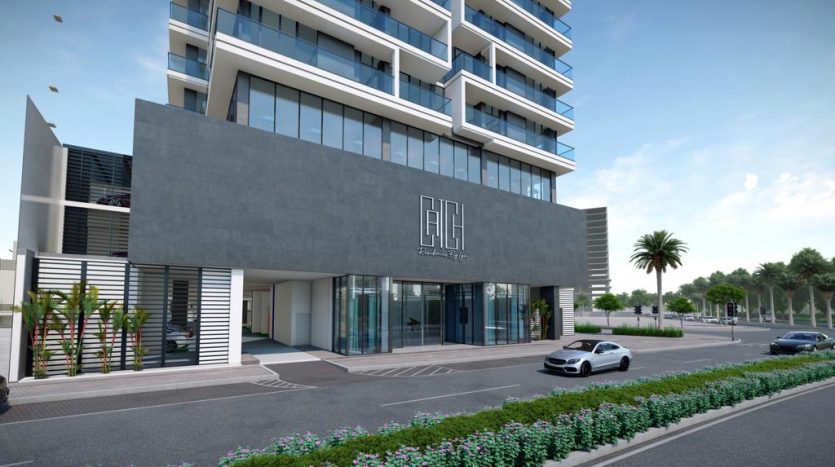Bâtiment moderne de plusieurs étages au design élégant avec une façade grise, de grandes fenêtres et une entrée spacieuse. Des palmiers et des arbustes bien entretenus bordent la rue pour capter le dynamisme de Dubaï.