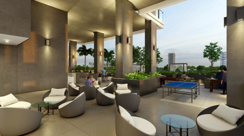 Coin salon extérieur moderne avec des sièges élégants, des plantes et une table de ping-pong au Catch Dubai, où les gens socialisent dans un cadre urbain au crépuscule.