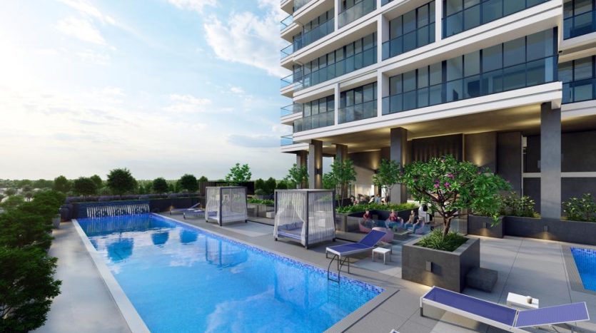 Immeuble résidentiel moderne de grande hauteur doté d&#039;une piscine extérieure, d&#039;espaces de détente luxueux, d&#039;une verdure luxuriante et d&#039;une architecture contemporaine sous un ciel dégagé de Dubaï.