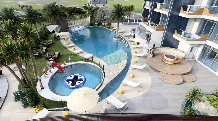 Vue aérienne d&#039;une piscine luxueuse du complexe Samana Waves Dubaï, entourée de palmiers, de chaises longues et d&#039;une architecture moderne, avec des gens profitant de la journée ensoleillée.