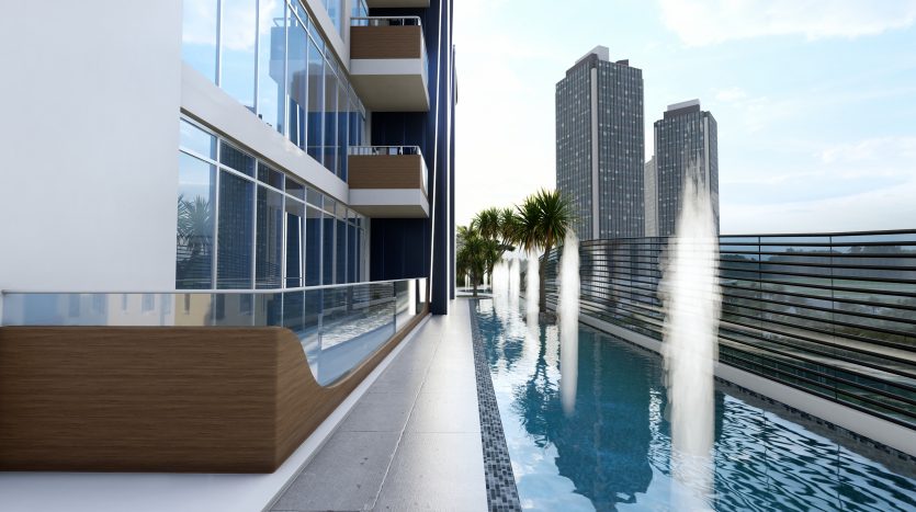 Balcon d&#039;appartement moderne avec une piscine étroite à Samana Waves, surplombant les grands immeubles de la ville de Dubaï sous un ciel bleu clair.