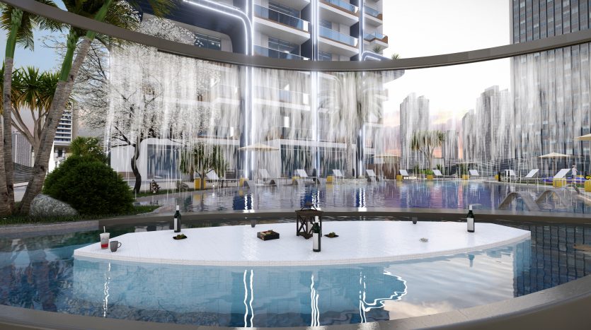 Une piscine extérieure avec un bar insulaire circulaire au centre, entourée de grands bâtiments urbains et de palmiers luxuriants, reflétant le paysage urbain moderne de Samana Waves Dubai.