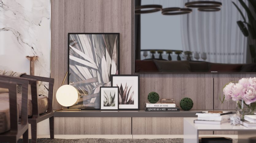 Un coin salon confortable et moderne dans un appartement de Dubaï comprenant une chaise en bois, une pile de livres et des œuvres d&#039;art encadrées au sol contre un mur en marbre et en bois, à côté d&#039;une fenêtre montrant un
