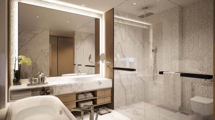 Une salle de bains luxueuse dans une villa à Dubaï avec des murs et un sol en marbre, comprenant une grande baignoire, une vasque avec double vasque, des miroirs et un espace douche séparé éclairé par un éclairage chaleureux.