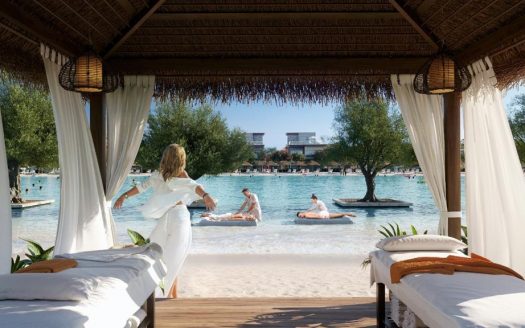 Une femme vêtue d'une robe blanche profite d'une vue panoramique sur un lagon relaxant avec des gens flottant sur des structures gonflables, depuis une cabane luxueuse ornée de lits moelleux et d'un décor naturel dans une villa exclusive de Dubaï.