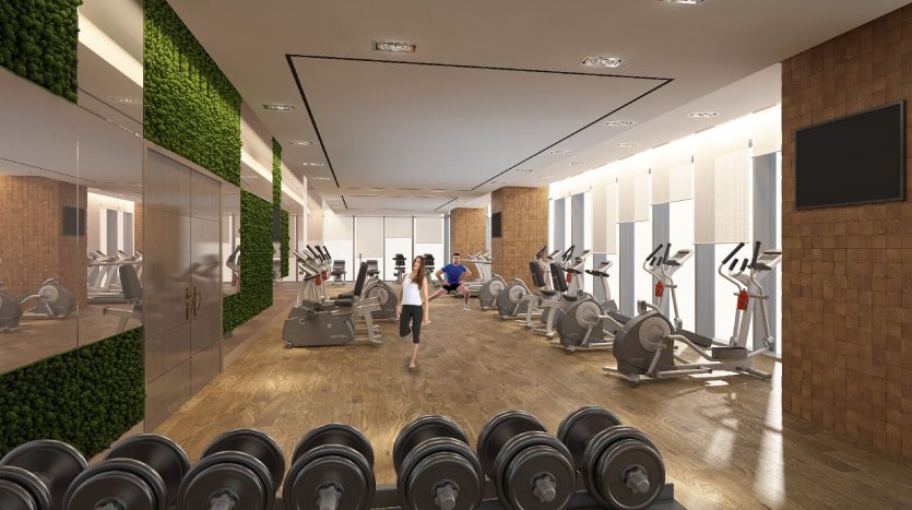 Une salle de sport spacieuse et moderne à Dubaï avec une variété d&#039;équipements, notamment des tapis roulants, des poids et des machines elliptiques, avec des murs en miroir et des accents de bois naturel. Une personne fait du jogging sur un tapis roulant