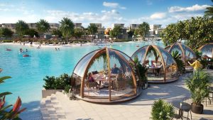 Une piscine extérieure du complexe où les gens se détendent et nagent, entourée de luxueuses salles à manger en forme de dôme où les clients prennent leurs repas. Une verdure luxuriante et des immeubles d'appartements modernes à Dubaï sont visibles en arrière-plan.