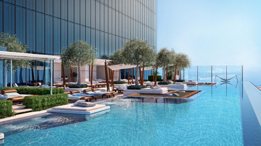 Luxueuse piscine à débordement sur le toit surplombant le paysage urbain de Dubaï, avec des cabanes, des chaises longues et des arbres en pot luxuriants sous un ciel bleu clair.