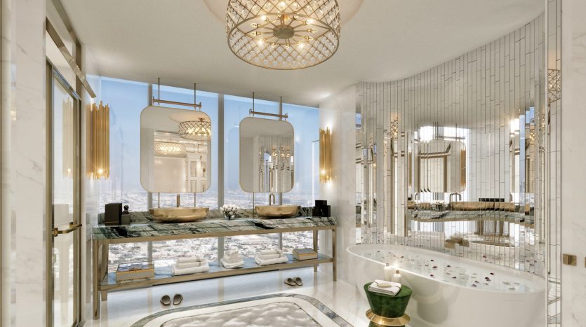 Salle de bains luxueuse avec sols et murs en marbre dans une propriété à Dubaï, comprenant une baignoire autoportante, des lavabos à double vasque, des miroirs ornés et une vue étincelante sur l&#039;océan à travers de grandes fenêtres.