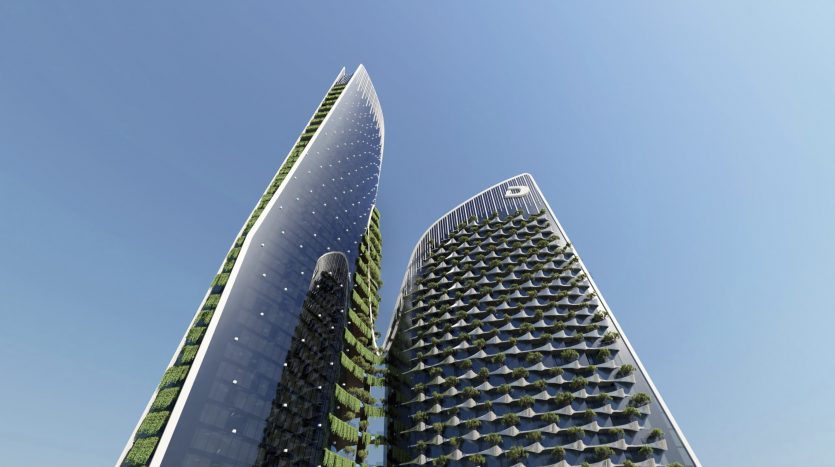 Deux gratte-ciel modernes recouverts de verdure sous un ciel bleu clair à Dubaï, reflétant une conception architecturale respectueuse de l&#039;environnement.